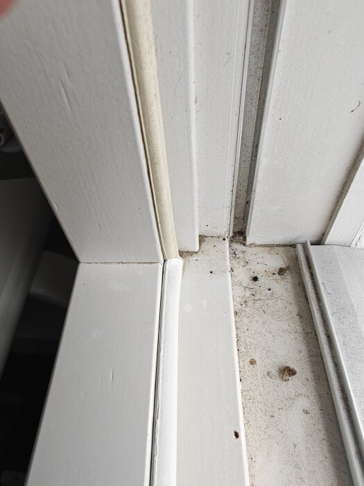 Närbild av en vit fönsterkarm med en nyligen bytt bottenlist som visar smuts och märken på ytan.