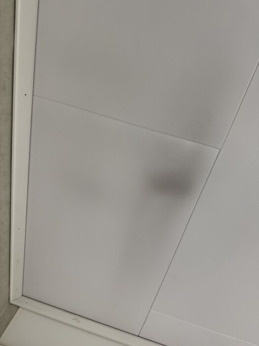 Tak med sotfläckar inomhus, synlig smuts på ljusa plattor.