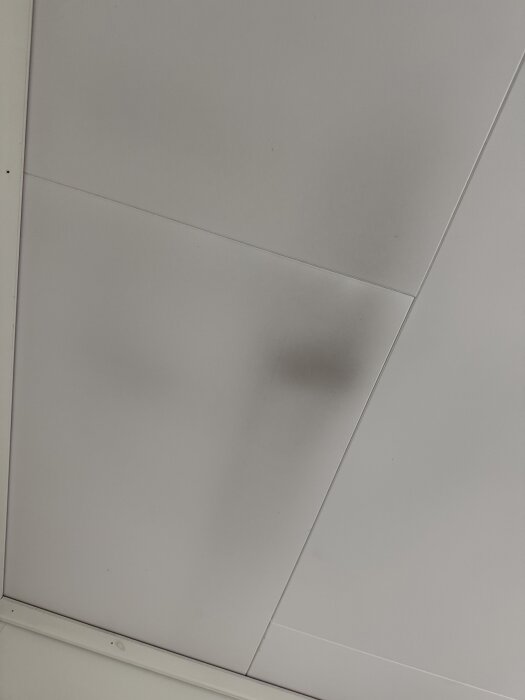 Svarta sotfläckar på vitt innertak, möjlig bakgrund till rökproblem i huset med öppen spis.