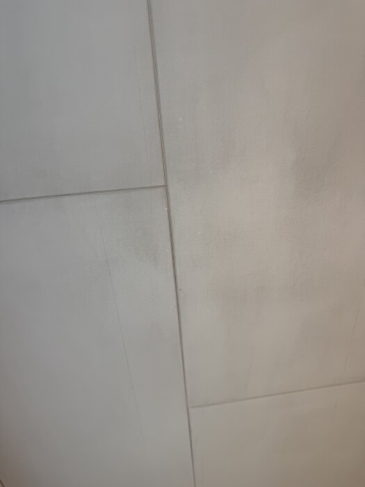 Närbild på ett väggparti med svarta sotfläckar och ljusare partier emellan, troligen orsakat av eldning i öppen spis.