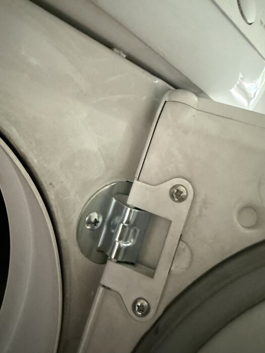 Närbild på en del av en torktumlare med insida av luckan, synligt täckt med sot eller smutspartiklar.