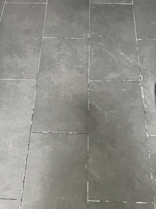 Svarta klinkerplattor med vita saltutfällningar i fogarna i en nyligen renoverad källare.