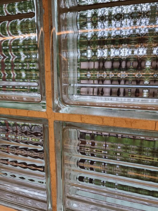 Sprucken fog mellan fyra glasblock, fokus på skadad och missfärgad fog.