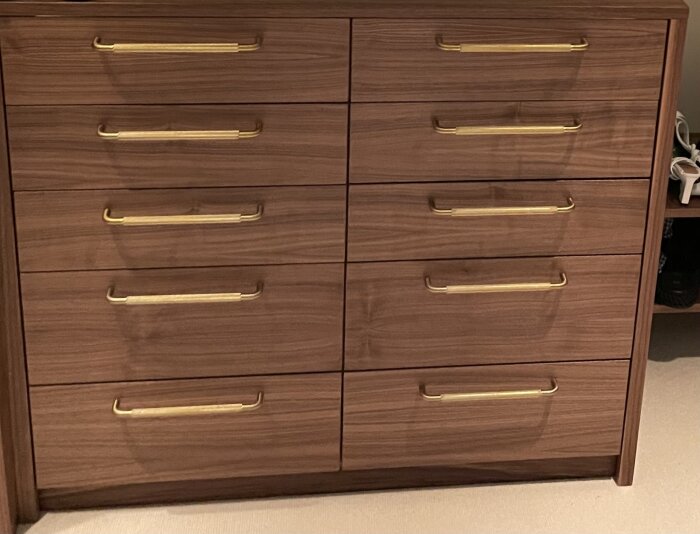 Träbyrå med nio lådor, var och en med guldfärgade handtag, troligtvis Perugia-modellen från Theofils, enligt inlägget.