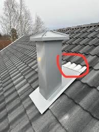 Skorsten på tak med skadad plåt, inringad i rött, visar hål där vatten läcker in. Plåten är tunn och behöver bytas ut.