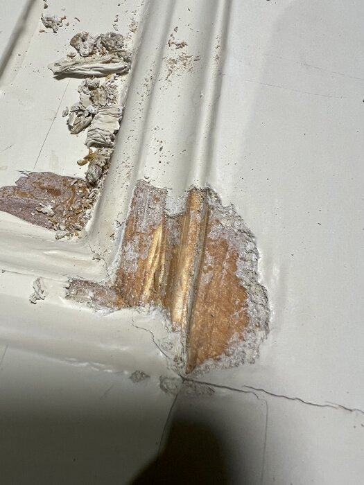 Flagnande färg och synligt trä på en gammal pardörr, delvis bortskrapad med smulor och mindre klumpar av färg.