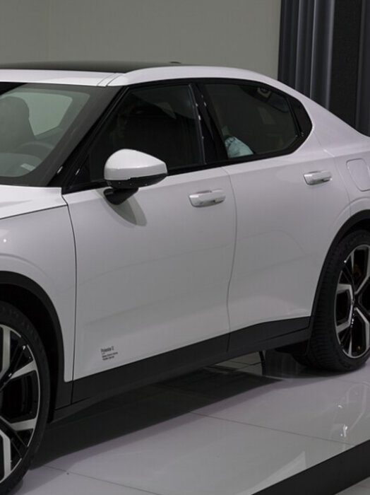 Vit Polestar 2, sedd från sidan, med svarta detaljer och stilrena linjer.