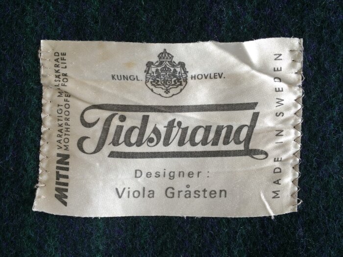 Etikett från Tidstrand-pläd designad av Viola Gråsten, med texten "MITIN varaktigt maläkra" och "Made in Sweden".