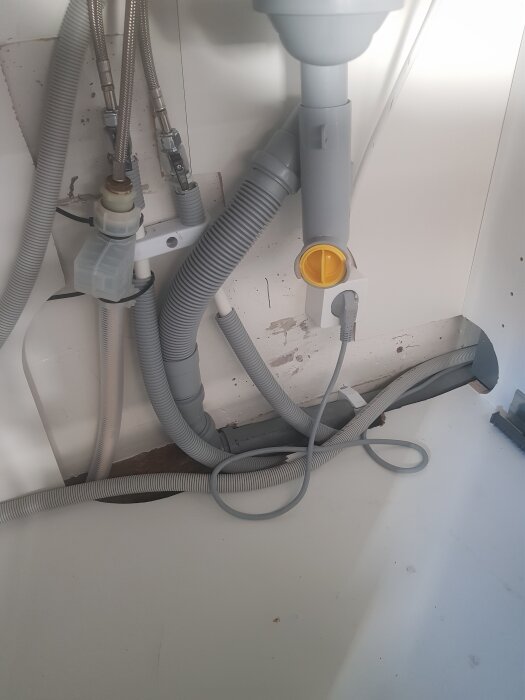 Rör under diskbänk med olika anslutningar, plastslangar och kopplingar, diskussion om att förebygga läckage genom användning av plastmatta och tätningsremsor.