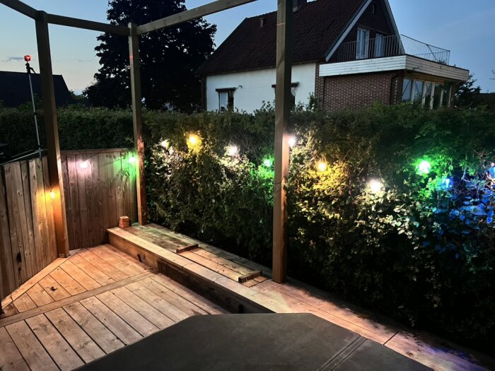 Pergola med färgglada lampor från Govee på kvällstid, pryder en inhägnad terrass.