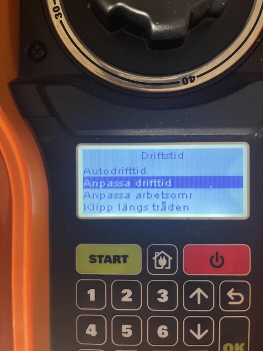 Display och knappar på en robotgräsklippare, visar menyalternativ för driftstid och anpassning av klipptider.
