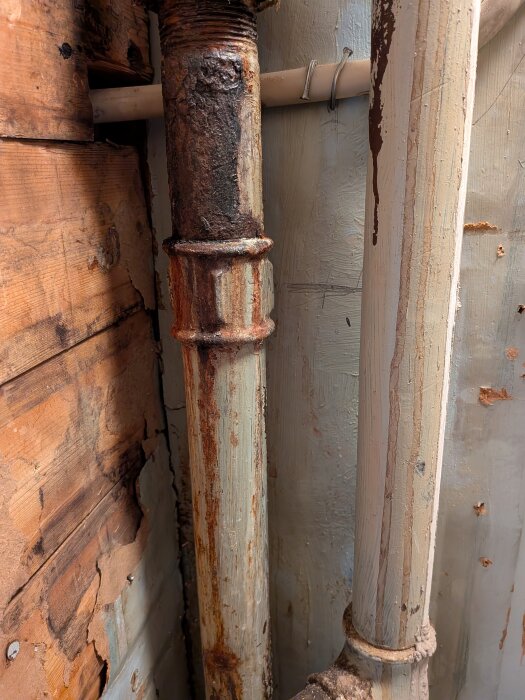 Rostigt rör med skadade gängor upptäckt bakom vägg under badrumsrenovering, visar potentiellt läckage och åldrande material.