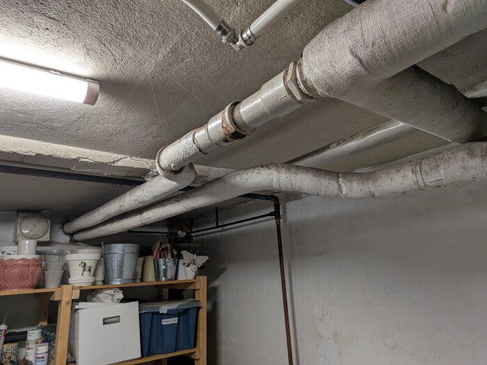 Äldre värmerör i källartaket med skarv och isolering, föreslagen renovering på grund av rötskadad skarv efter en liten långvarig läcka.