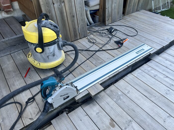 Sänksåg med dammsugare på en träplattform under ett byggprojekt.