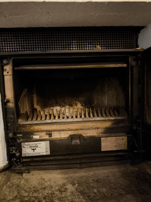 Öppen kamin med synliga styrreglage och askgaller, omgiven av instruktioner och växlar för luftflöde och aska på vänster och höger sida.