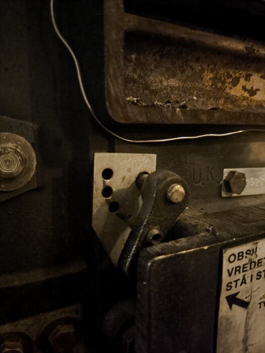 Spak med flera hål för justering bredvid en stängd lucka på en ugn, del av en diskussion om eldreglering och askhantering.