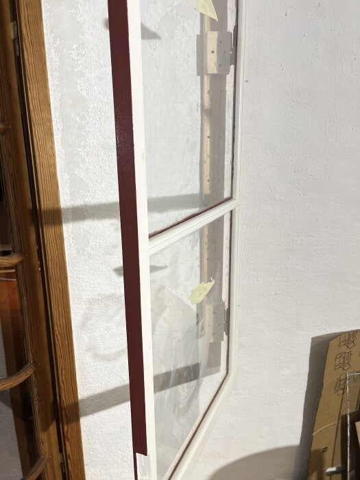 Färdigställd ytterbåge med glas och röd/vit färg, fotograferad mot en vit vägg.