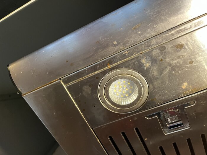 Inbyggd lampa i en rostig fläkt, del av diskussion om att ta loss lampinsatsen.