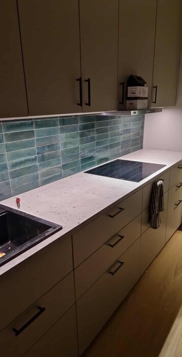 Köksbänk med kaklad vägg och 1 mm fog, spishäll och diskho synliga.