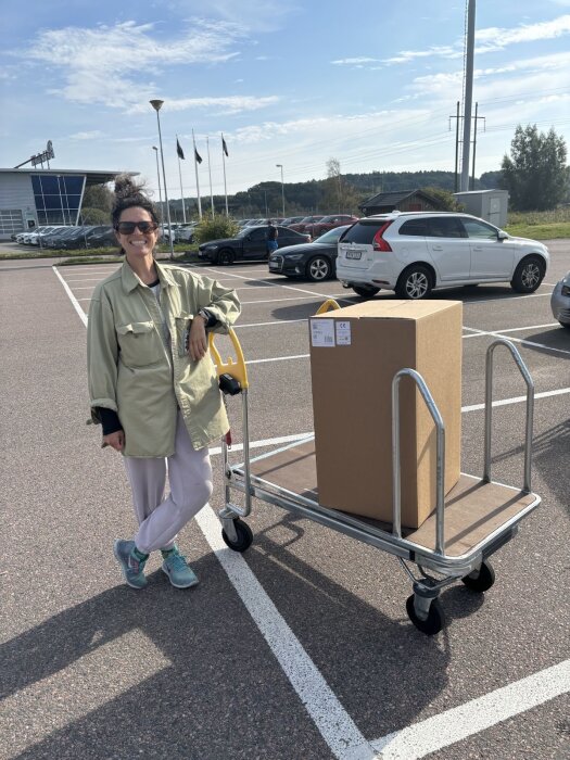 Person vid en byggvaruhandels parkering bredvid en lastvagn med en kartong, möjligtvis innehållande ett Harvia M3 aggregat.