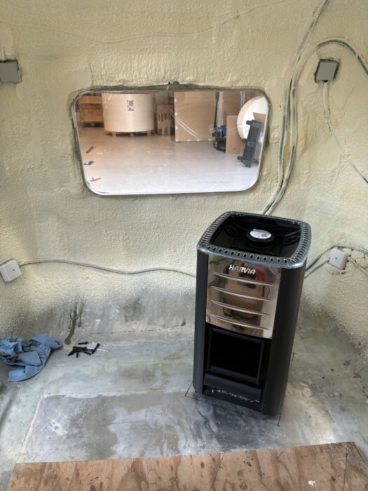 Harvia M3 bastuaggregat står på ett betonggolv i en husvagn med utsikt genom ett fönster mot ett lagerutrymme.