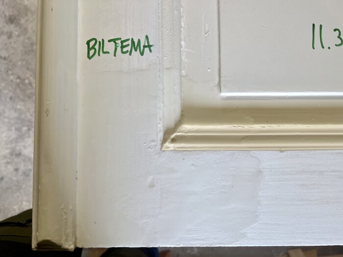 Detaljbild av dörrkant med text "Biltema", visar ett lager färg med lite borttagningseffekt efter kemisk färgborttagning.