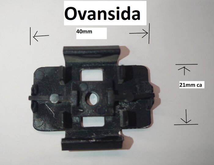 Svart plastclip för montering, med måtten 40 mm x 21 mm, visas ovanifrån. Används för att fästa aluminiumprofiler vid karmar.
