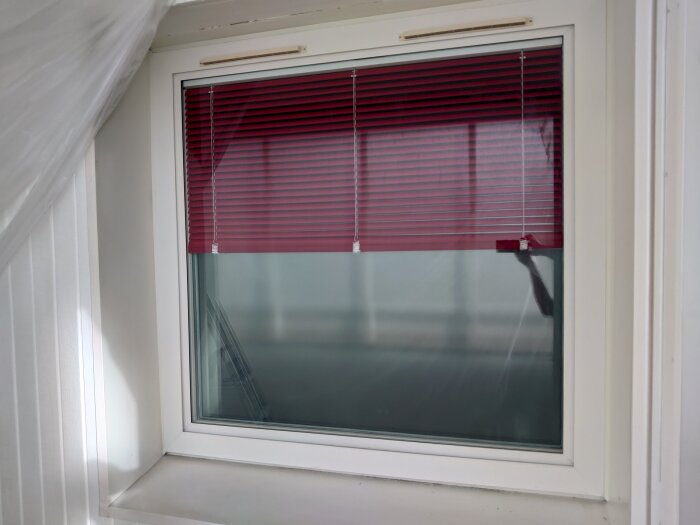 Fönster med röd persienn, aluminiumprofiler och monterade plåtar runtom. Fönstret ska målas om enligt diskussionsinlägget om clips.