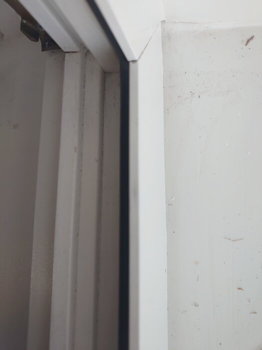 Aluminiumfoder på dörrkarm med clips, monterat mot vit vägg. Synliga skruvhål och smutsfläckar. Behöver nya clips för demontering.