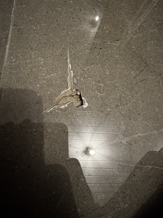 Klinkergolv med en skadad platta som har ett hål och sprickor. Skadan finns på en 60x60 cm platta, beskrivet i renoveringsdiskussion.