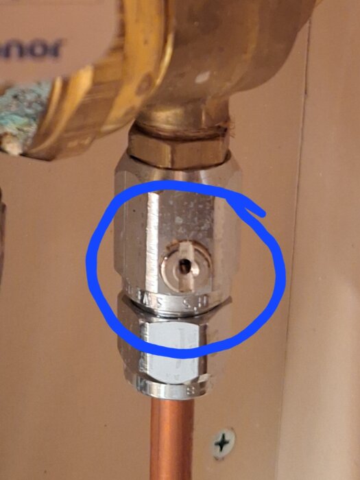 En inringad ventil på en rörkoppling med en skruvmejselslits för justering.