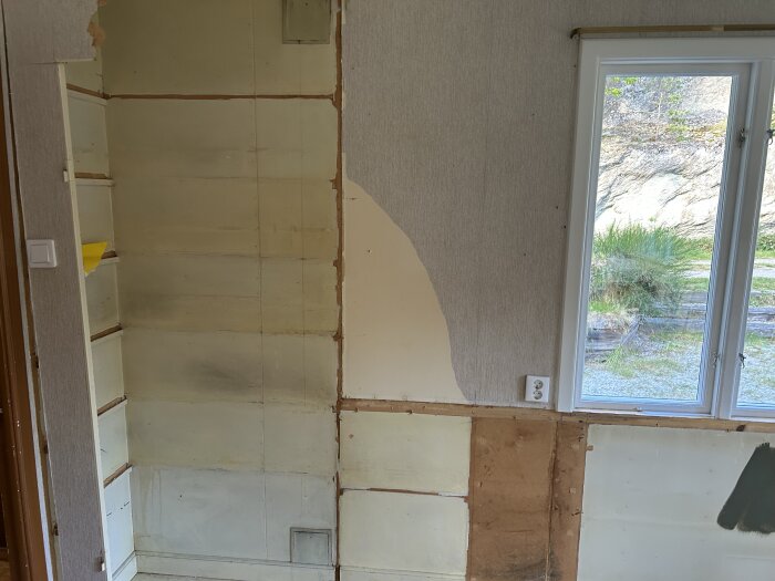 Vägg med delvis borttagen tapet och blottad gips, bredvid fönster. Fråga om bästa sätt att jämna ut för målning.