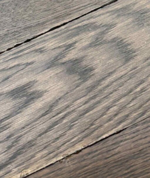 Ljusa slipmärken och ojämna skarvar på ett trägolv, med överdrivet slipade områden och pigmenteringsfel.