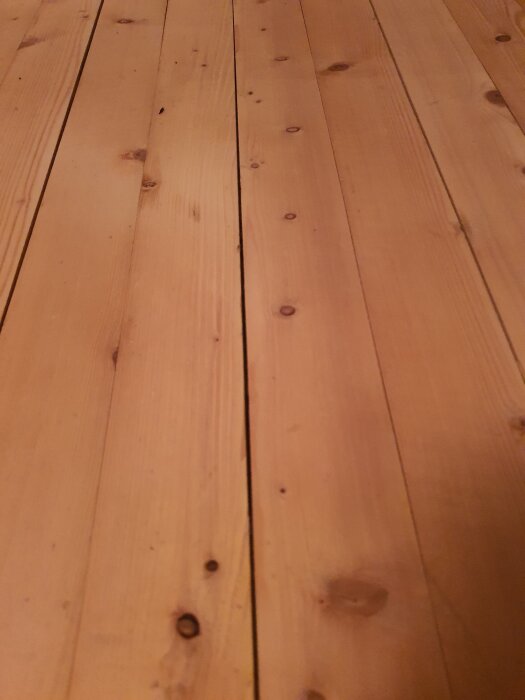 Närbild av trägolv med variation i repor och struktur, diskuterar behovet av omslipning.