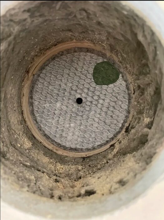 Rund hålkärna i vägg med ett genomträngt material som kan vara eternit.