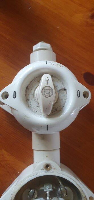 Gammal strömbrytare med vridbar knapp markerad med "0" och "1", monterad på en brun träyta, diskuteras för funktion och koppling.