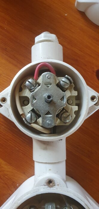 Gammal elektrisk brytare med synliga trådanslutningar och skruvar, monterad på brun träyta.