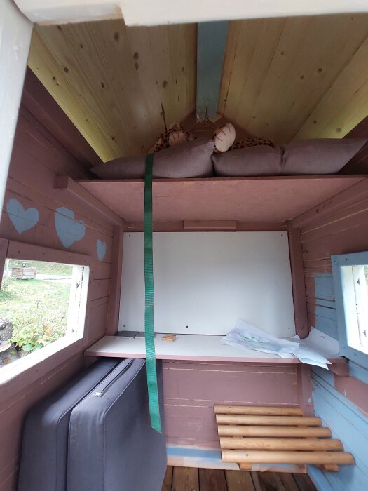 Invändigt i lekstugan med hemligt loft för barn, dekorationer och färgstänk synliga på väggarna.