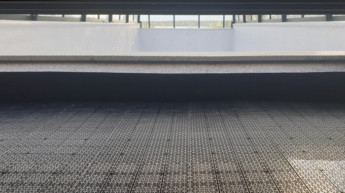 Poolområde med svart golv och del av poolhus.