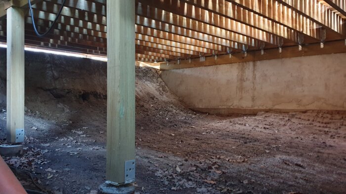 Under poolhusets förhöjda golv med trästöd och jordgolv syns utrymme för poolöverdraget att glida in.