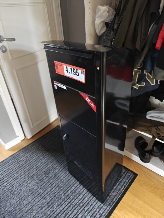 Svart brevlåda placerad i en hall, märkt med ett pris på 4195 kronor.