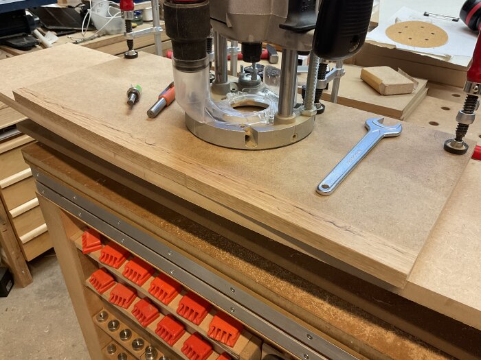 Fräsning av eklist på arbetsbänk med verktyg som handöverfräs, skruvnyckel och borr.