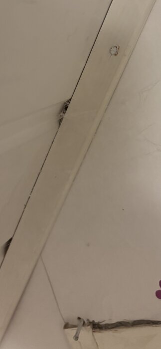 Närbild av takhörn med vad som verkar vara damm, spindelnät eller mögel vid skarven.