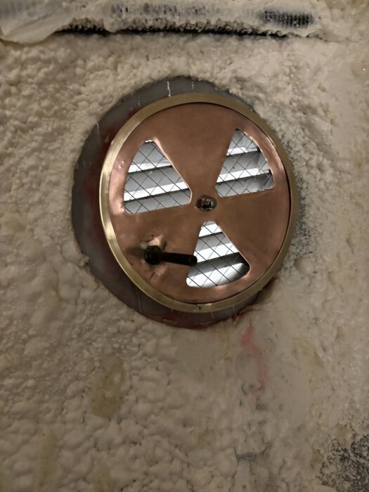 Kopparventil installerad i bastuvagnens vägg med synligt ventilationsgaller och handtag.