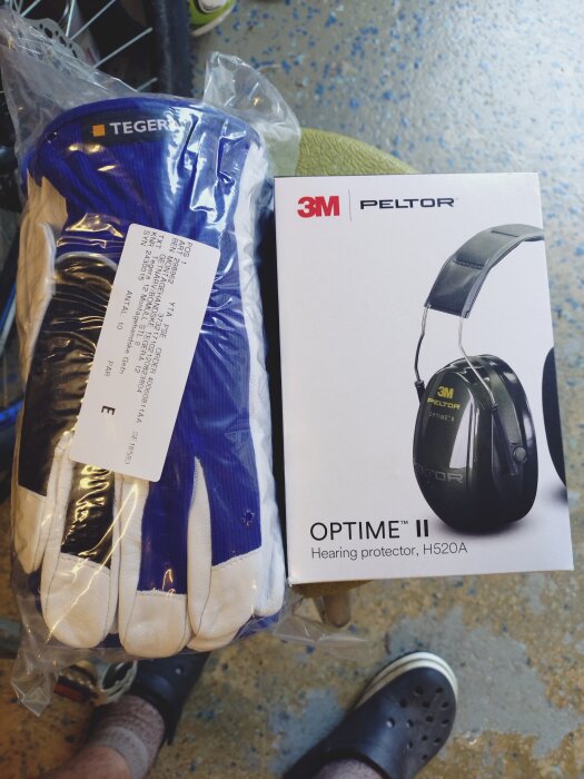 Skyddshandskar och ett par hörselskydd från 3M Peltor Optime II ligger sida vid sida.
