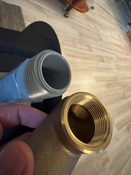 Närbild av två rörkopplingar, en i plast och en i metall, visar olika typer av gängor i en diskussionspost om hydropress-installation.