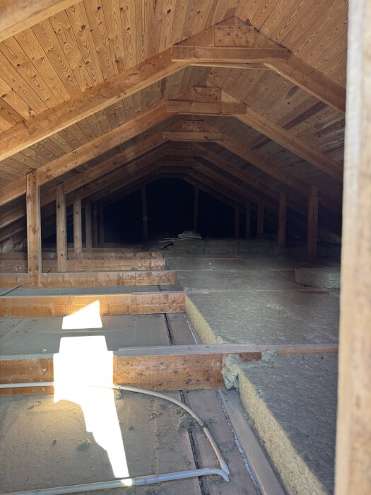 Takstolar i träkonstruktion på vinden över ett garage, förberedelse för att riva mellanvägg och skapa dubbelgarage.