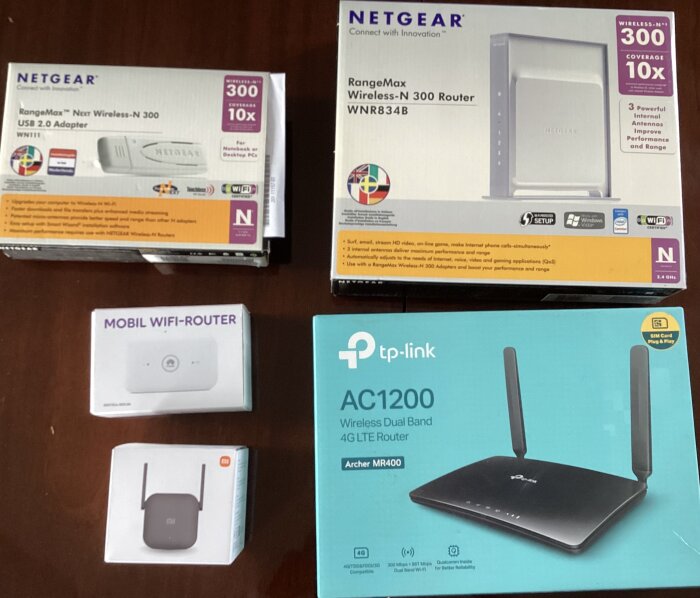 Olika routrar och nätverksenheter från Netgear, TP-Link och Xiaomi ligger på ett bord, inklusive en mobil WiFi-router.