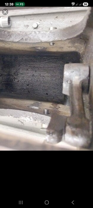 Inre vy av en metallstruktur med fästen och skruvar, potentiellt relaterat till mekanisk montering eller reparation.