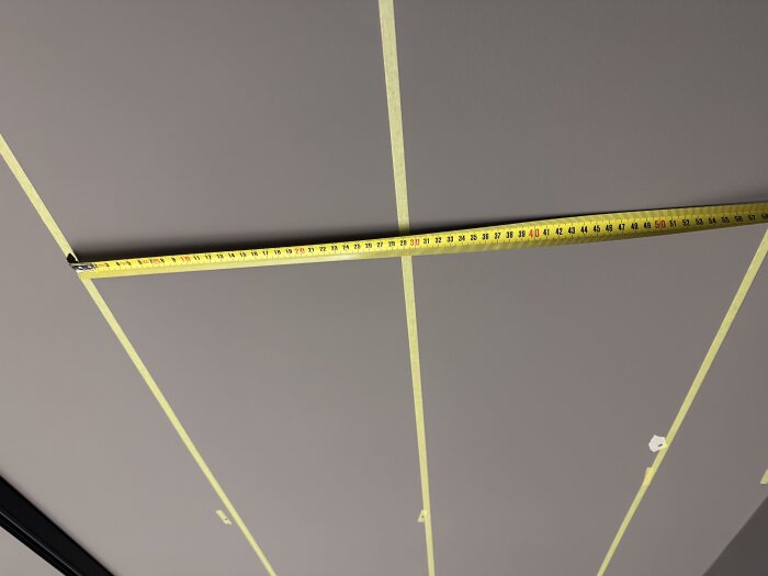 Måttband och tejpade linjer på ett tak, används för att mäta avstånd för att placera ett fäste.